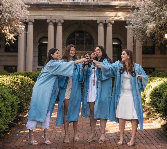 Four graduates cheers with champagne in front of Milbank